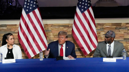 Former President Trump, a Republican presidential candidate, speaks at a campaign event Saturday, June 15, 2024, in Detroit, as Itasha Dotson and Carlos Chambers listen. (AP Photo/Carlos Osorio)