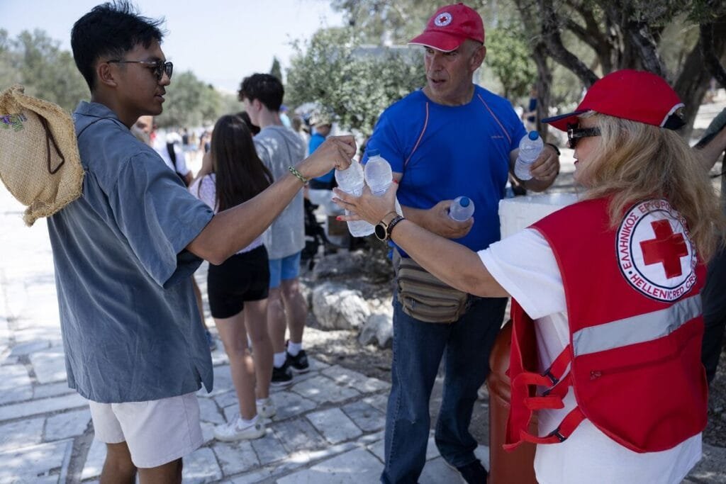Red Cross workers distribute water to visitors outside the Acropolis in Athens on July 13.Photographer: Angelos Tzortzinis/Getty Images