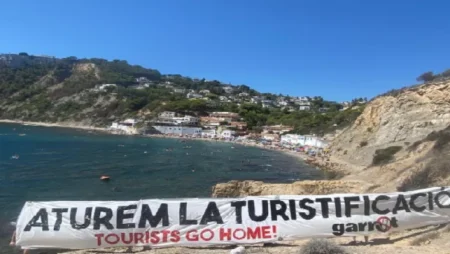 Protestors unfurled a huge banner telling tourists on a packed Costa Blanca beach on Sunday to "go home".