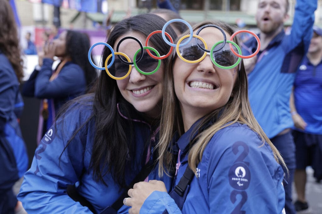 Volunteers pose with Olympic ring sunglasses at the parade. © Andre Pain, AFP