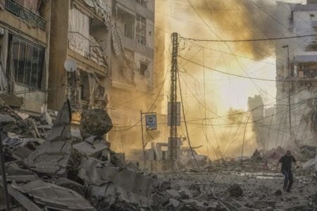 A man runs for cover after an Israeli airstrike in Beirut’s Dahiyeh suburb on Friday. (Hassan Ammar / Associated Press)