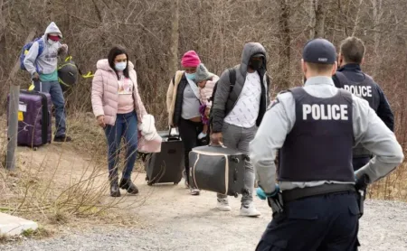 FILE PHOTO: Asylum seekers cross into Canada from the U.S. border near a checkpoint on Roxham Road near Hemmingford, Quebec, Canada April 24, 2022. REUTERS/Christinne Muschi/File Photo