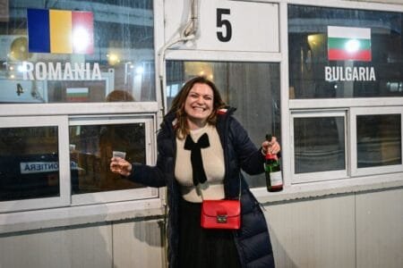 A Bulgarian woman celebrates at a checkpoint at the Giurgiu-Ruse border between Romania and Bulgaria on January 1, 2025 [Daniel Mihailescu/AFP]