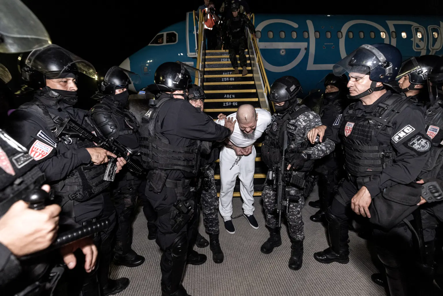 An alleged migrant gang member getting removed from the plane by El Salvadoran authorities